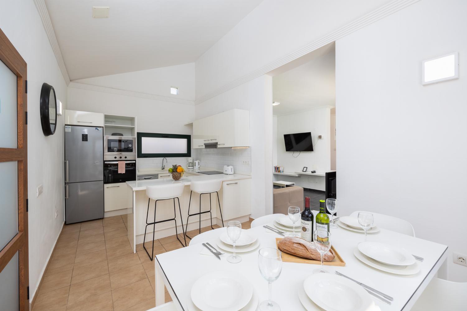Open-plan living room with sofa, dining area, kitchen, ornamental fireplace, A/C, WiFi internet, and satellite TV