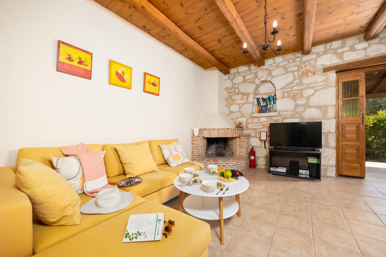 Open-plan living room with sofa, dining area, kitchen, ornamental fireplace, A/C, WiFi internet, and satellite TV