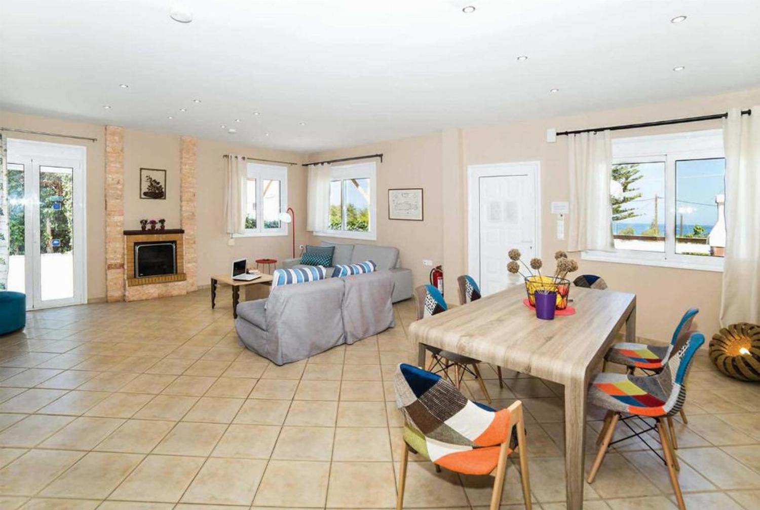 Open plan living room with comfortable sofas, ornamental fireplace, TV, patio doors, 