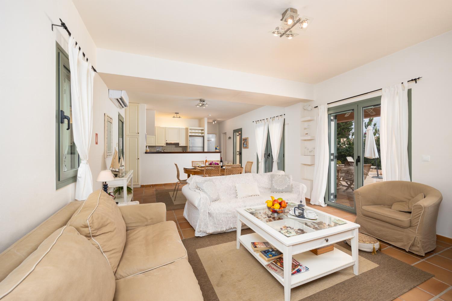 Open-plan living room with sofas, dining area, kitchen, A/C, WiFi internet, and satellite TV