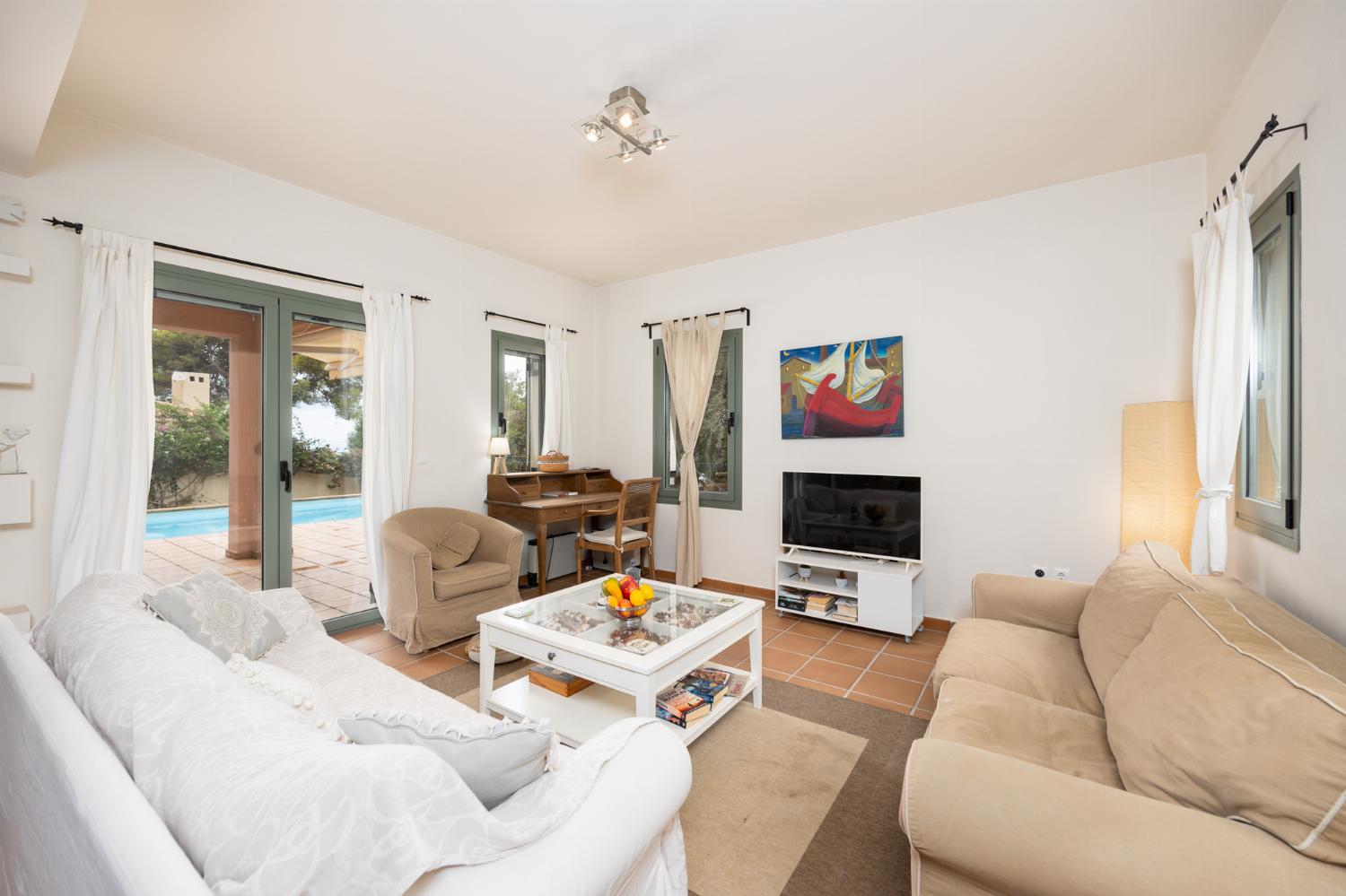 Open-plan living room with sofas, dining area, kitchen, A/C, WiFi internet, and satellite TV