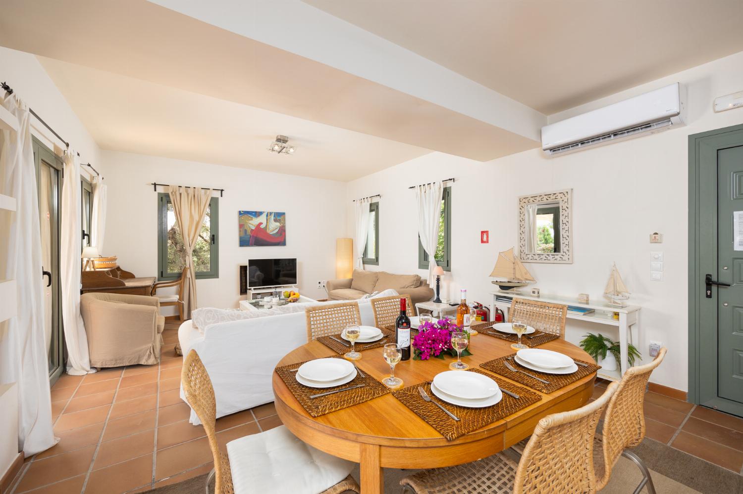 Open-plan living room with sofas, dining area, kitchen, A/C, WiFi internet, and satellite TV