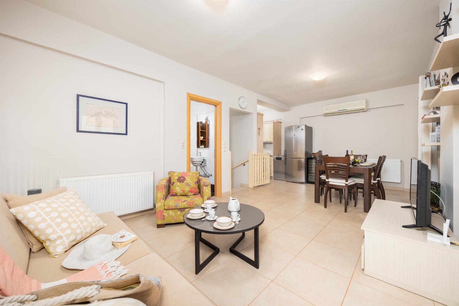 Open-plan living room with sofa, dining area, kitchen, A/C, WiFi internet, and satellite TV