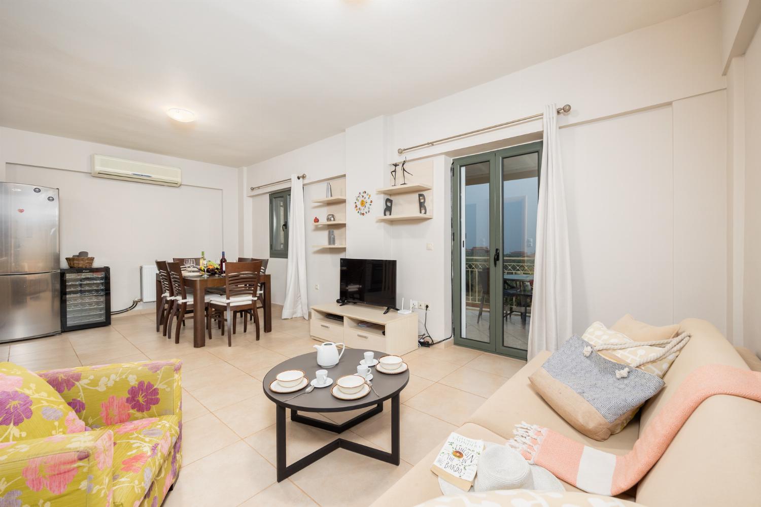 Open-plan living room with sofa, dining area, kitchen, A/C, WiFi internet, and satellite TV