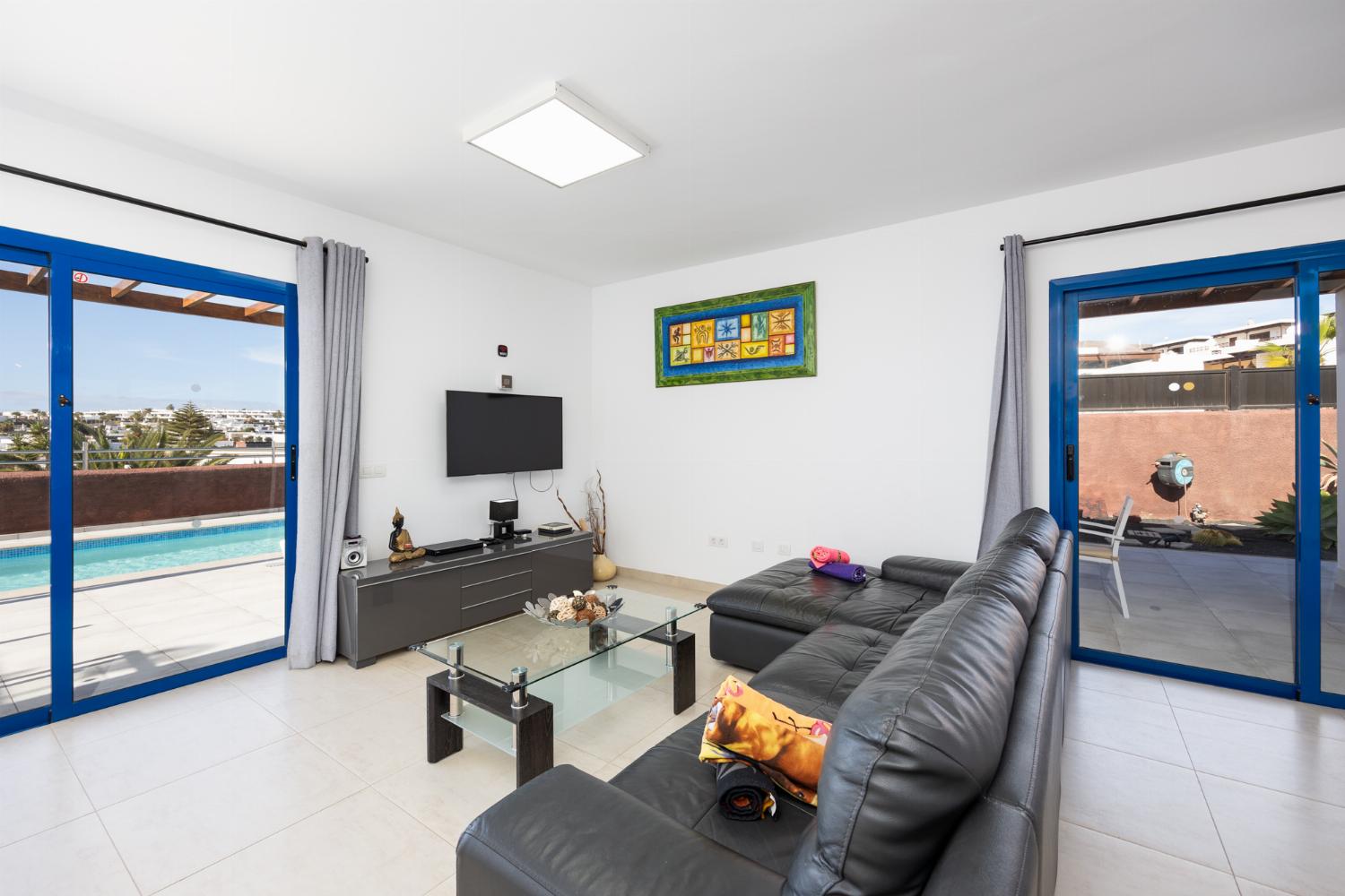 Open-plan living room with sofa, dining area, kitchen, A/C, WiFi internet, and satellite TV