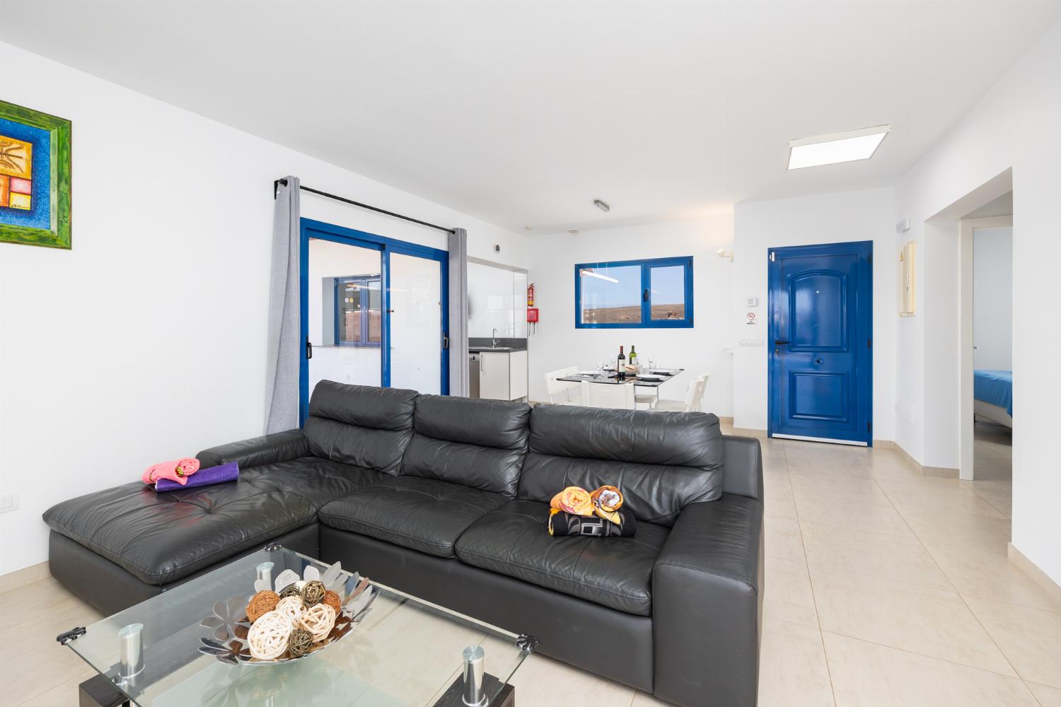 Open-plan living room with sofa, dining area, kitchen, A/C, WiFi internet, and satellite TV