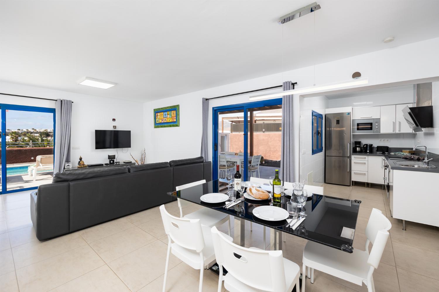 Open-plan living room with sofa, dining area, kitchen, A/C, WiFi internet, and satellite TV