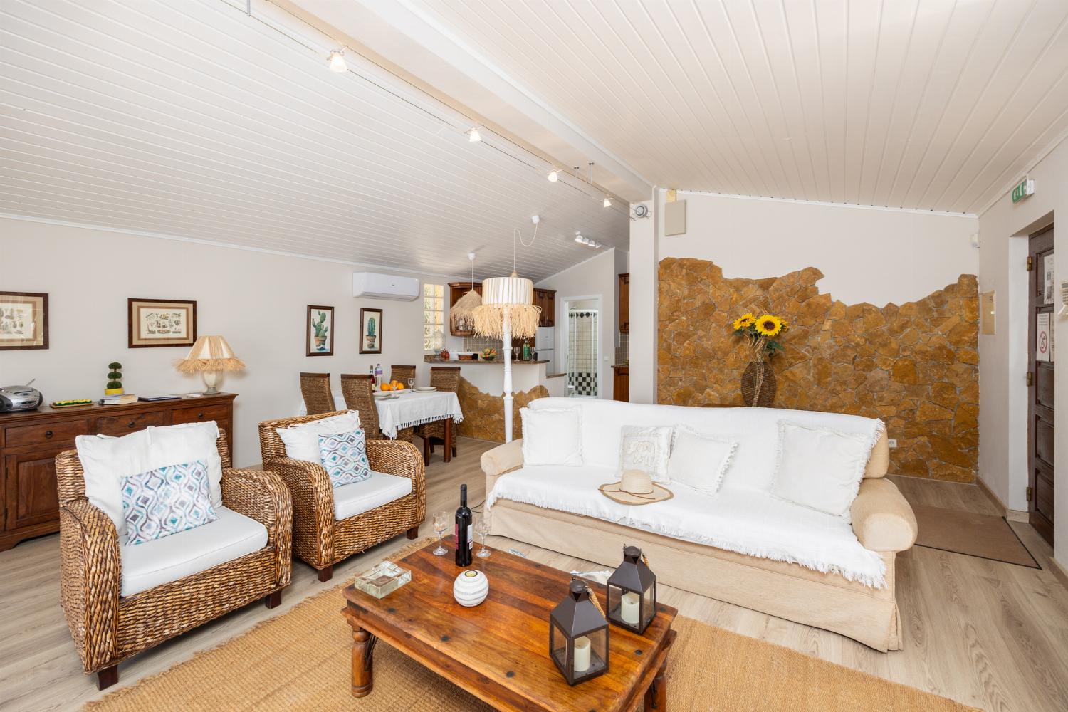 Open-plan living room with sofa, dining area, kitchen, A/C, WiFi internet, and satellite TV