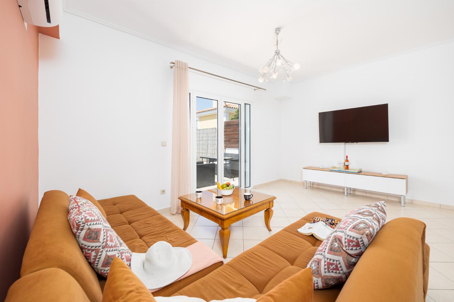 Open-plan living room with sofa, dining area, kitchen, A/C, WiFi internet, and satellite TV