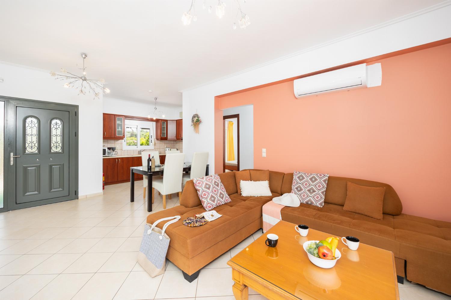 Open-plan living room with sofa, dining area, kitchen, A/C, WiFi internet, and satellite TV