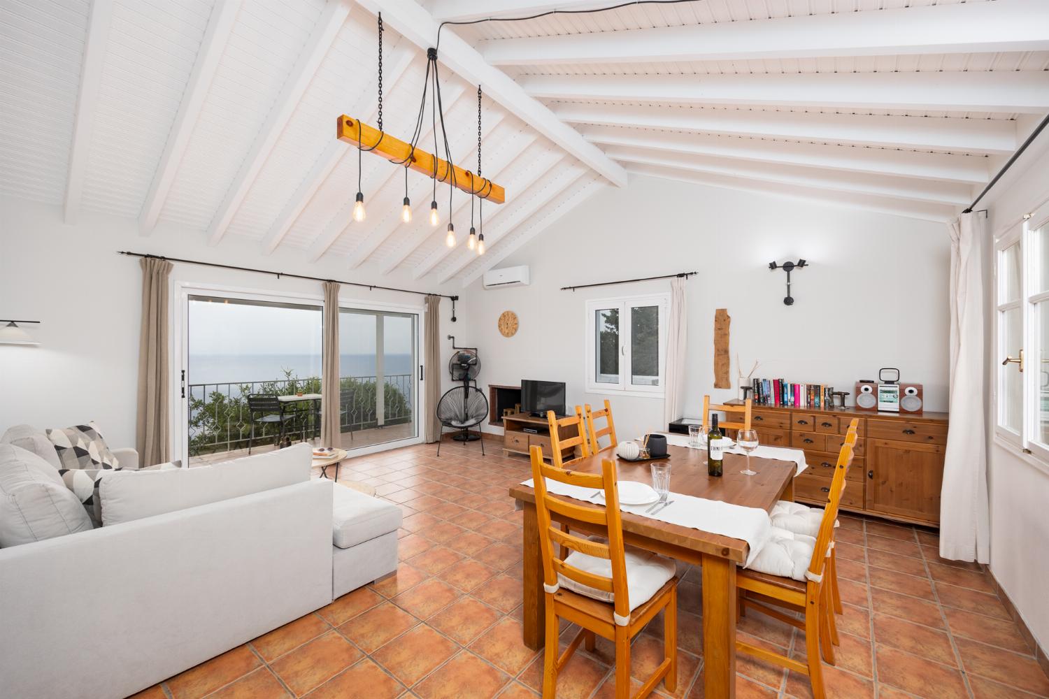 Open-plan living room with sofa, dining area, kitchen, ornamental fireplace, A/C, WiFi internet, satellite TV, and sea views