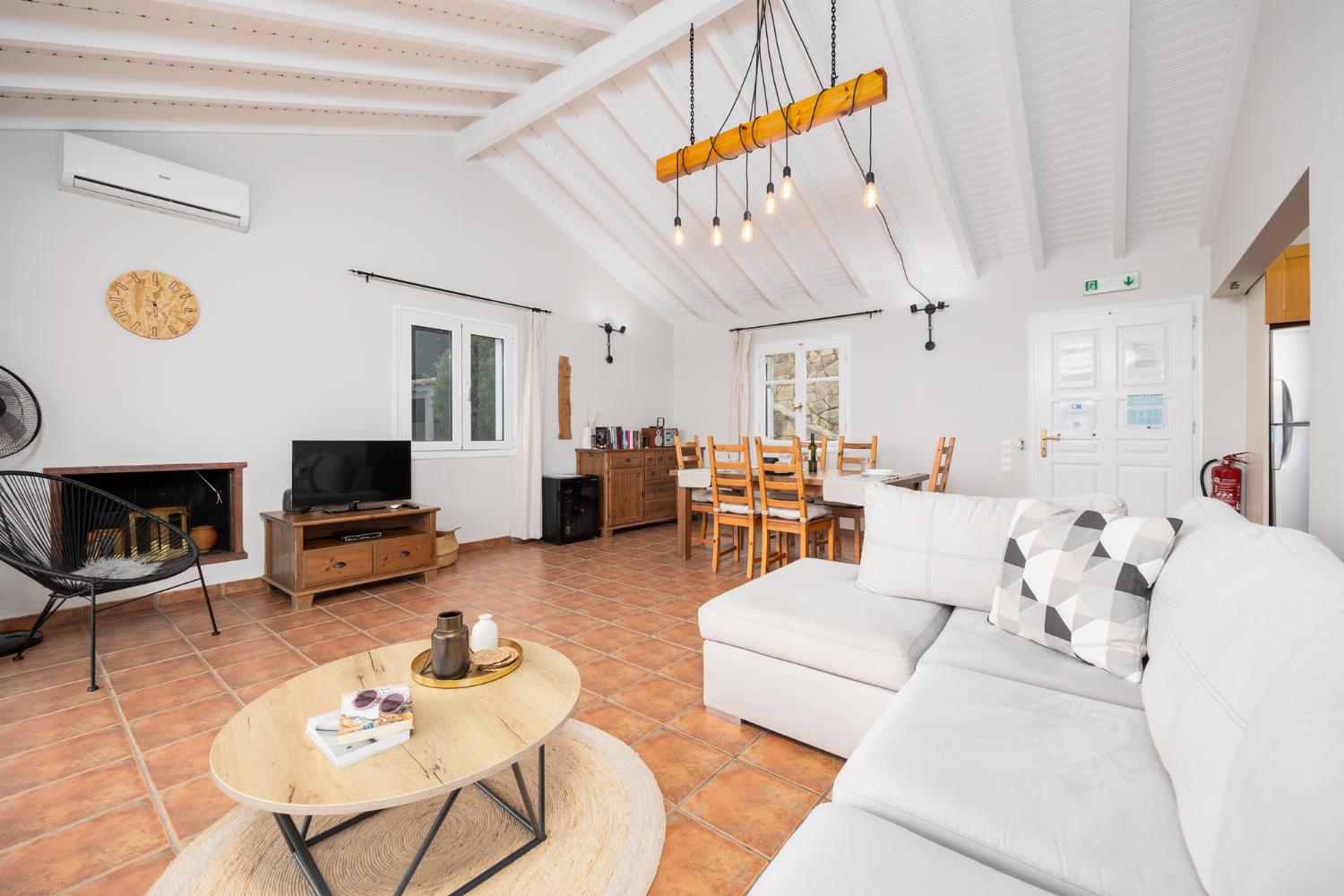 Open-plan living room with sofa, dining area, kitchen, ornamental fireplace, A/C, WiFi internet, satellite TV, and sea views
