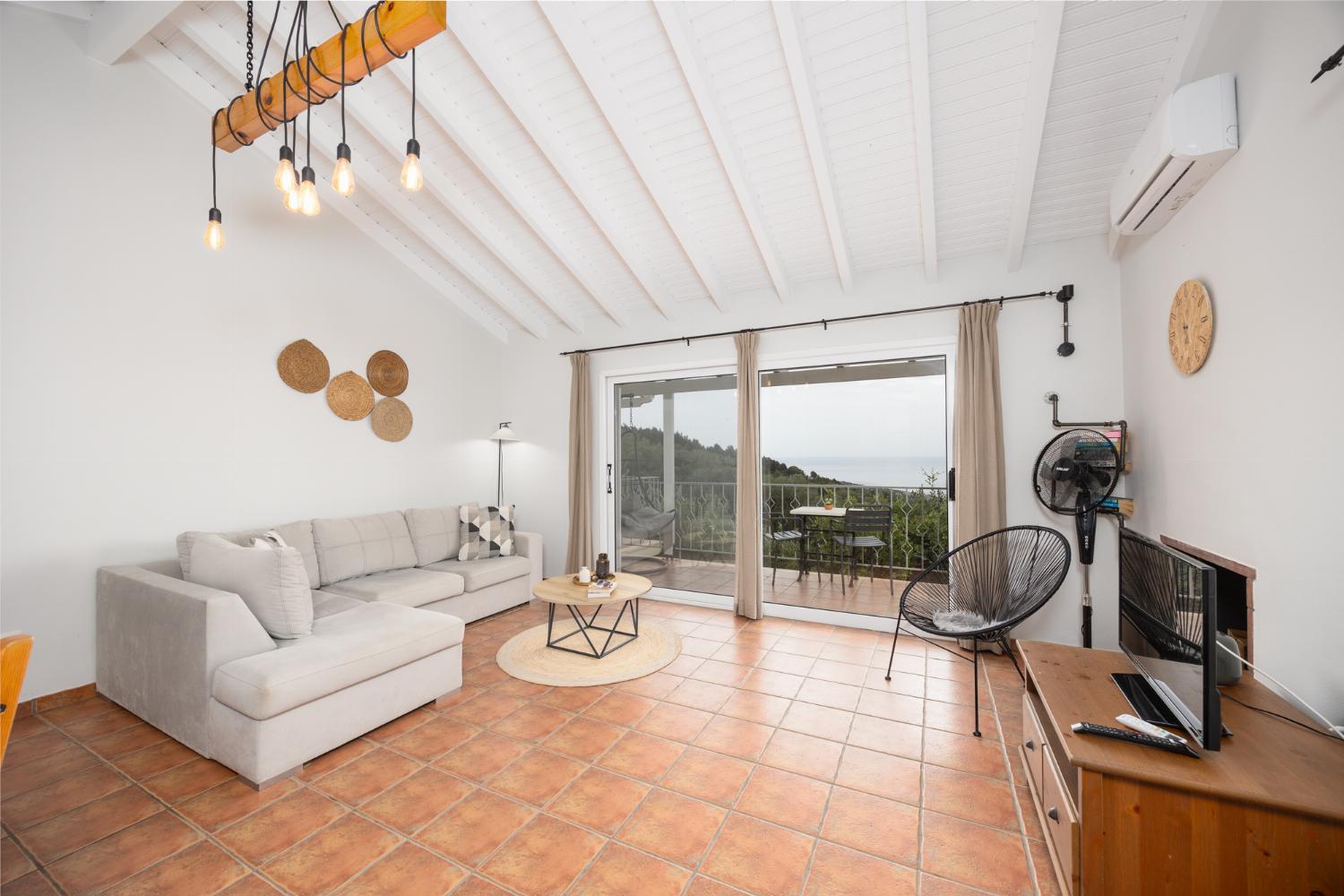 Open-plan living room with sofa, dining area, kitchen, ornamental fireplace, A/C, WiFi internet, satellite TV, and sea views