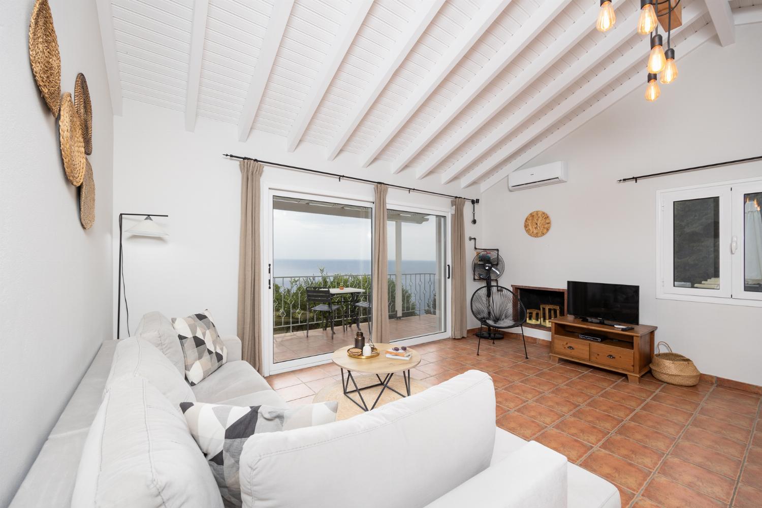Open-plan living room with sofa, dining area, kitchen, ornamental fireplace, A/C, WiFi internet, satellite TV, and sea views
