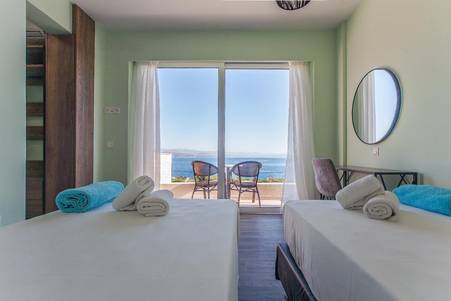 Twin bedroom with en suite bathroom, A/C, and balcony access with panoramic sea views