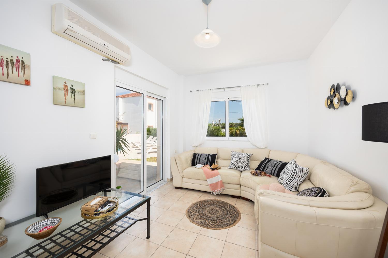 Open-plan living room with sofa, dining area, kitchen, A/C, WiFi internet, and satellite TV
