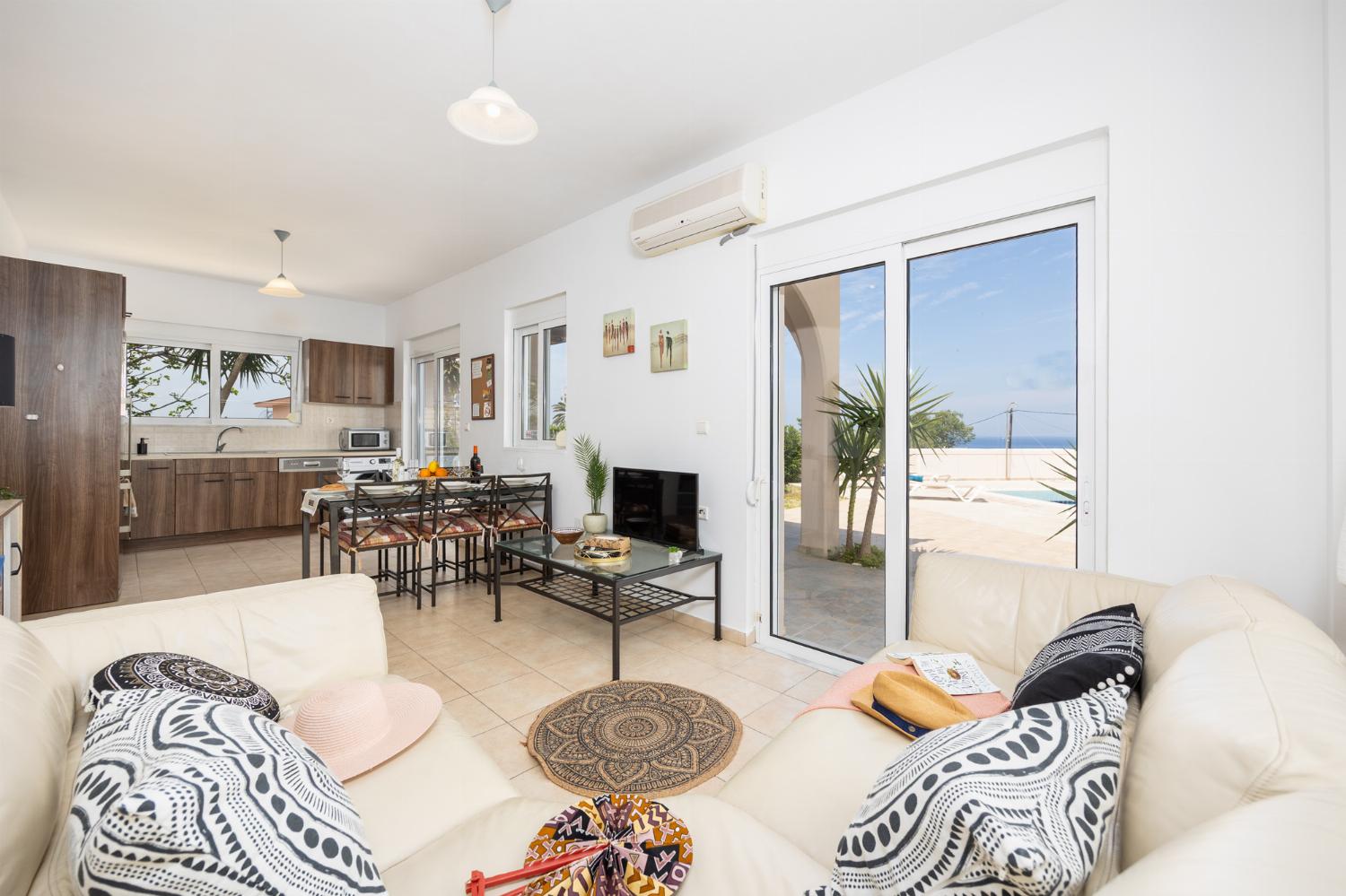 Open-plan living room with sofa, dining area, kitchen, A/C, WiFi internet, and satellite TV