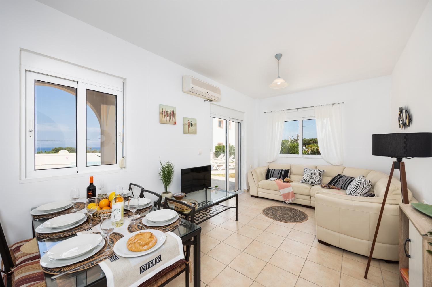Open-plan living room with sofa, dining area, kitchen, A/C, WiFi internet, and satellite TV