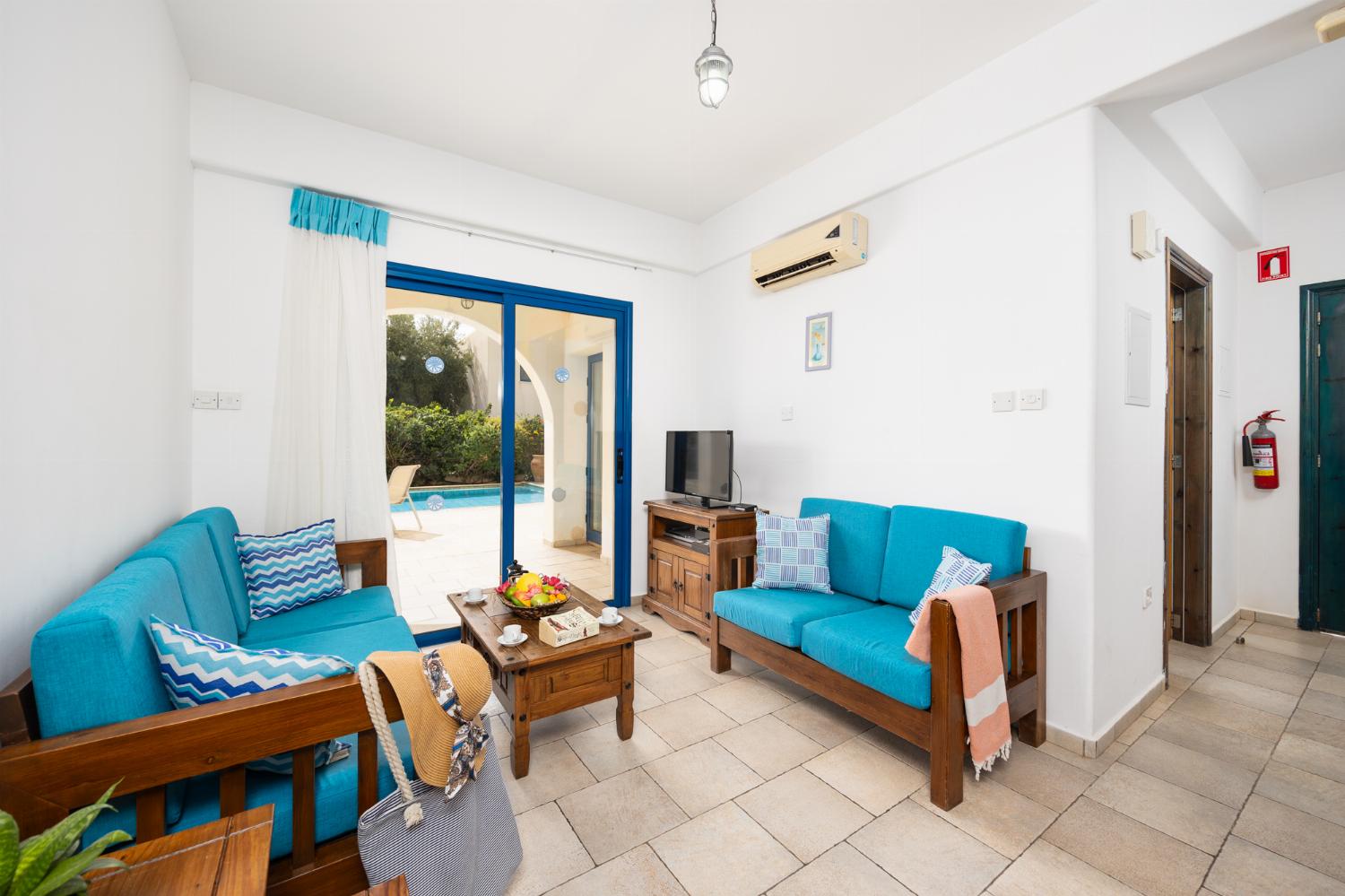 Open-plan living room with sofas, dining area, kitchen, A/C, WiFi internet, and satellite TV