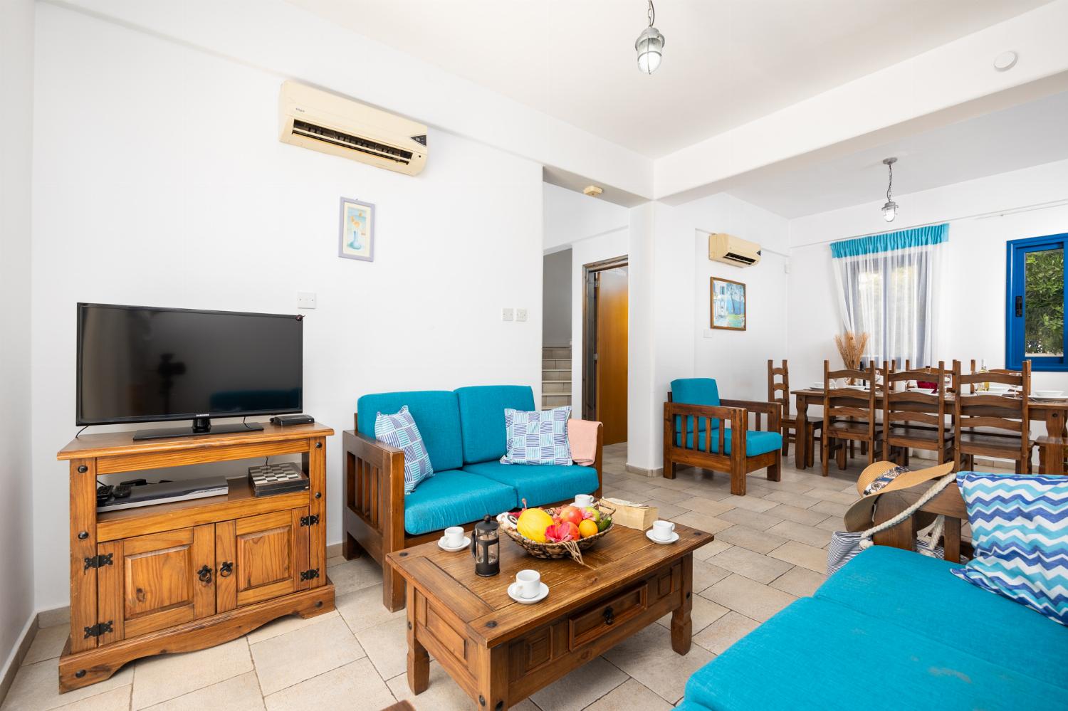 Open-plan living room with sofas, dining area, kitchen, A/C, WiFi internet, and satellite TV