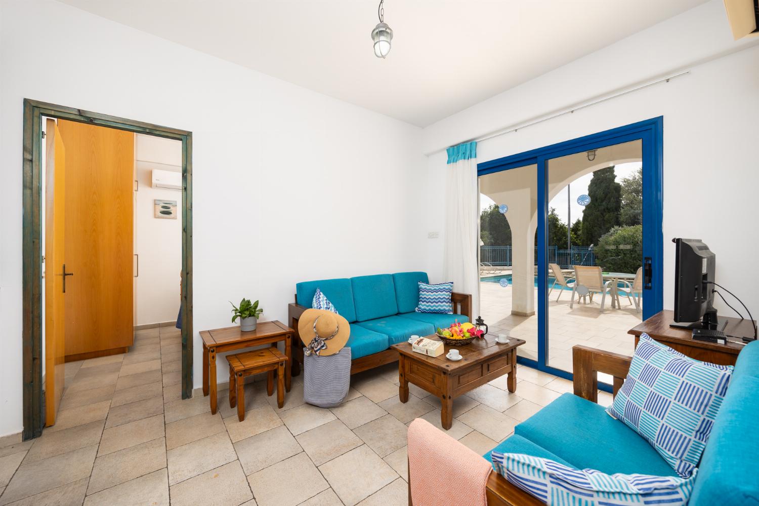 Open-plan living room with sofas, dining area, kitchen, A/C, WiFi internet, and satellite TV