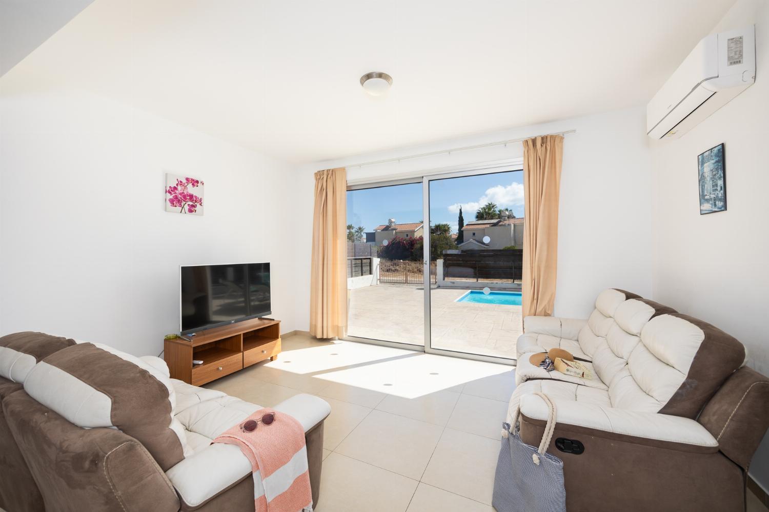 Open-plan living room with sofas, dining area, kitchen, A/C, WiFi internet, and satellite TV
