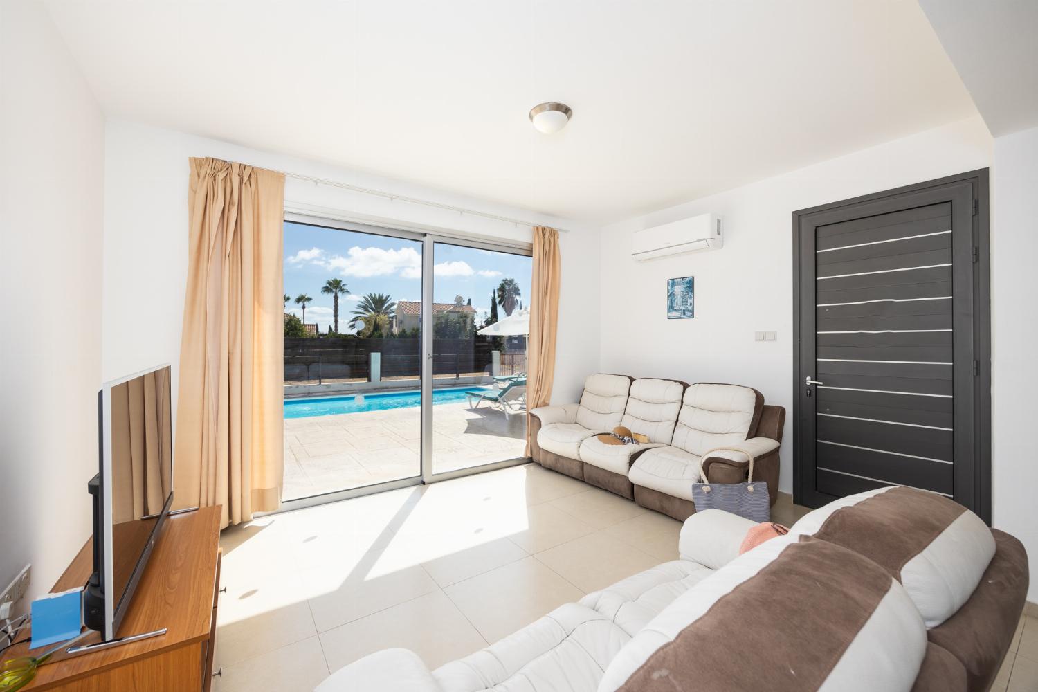 Open-plan living room with sofas, dining area, kitchen, A/C, WiFi internet, and satellite TV