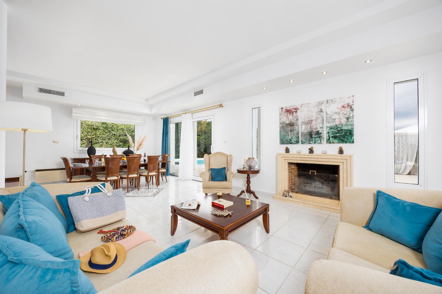 Open-plan living room on first floor with sofas, dining area, kitchen, ornamental fireplace, A/C, and WiFi internet
