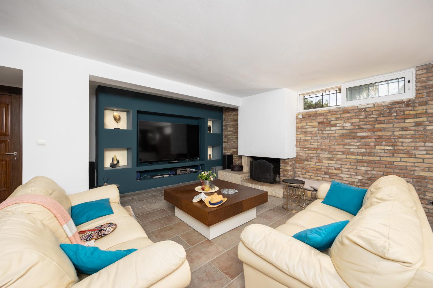 Open-plan living room on ground floor with sofas, dining area, bar area, ornamental fireplace, gym area, WiFi internet, and satellite TV