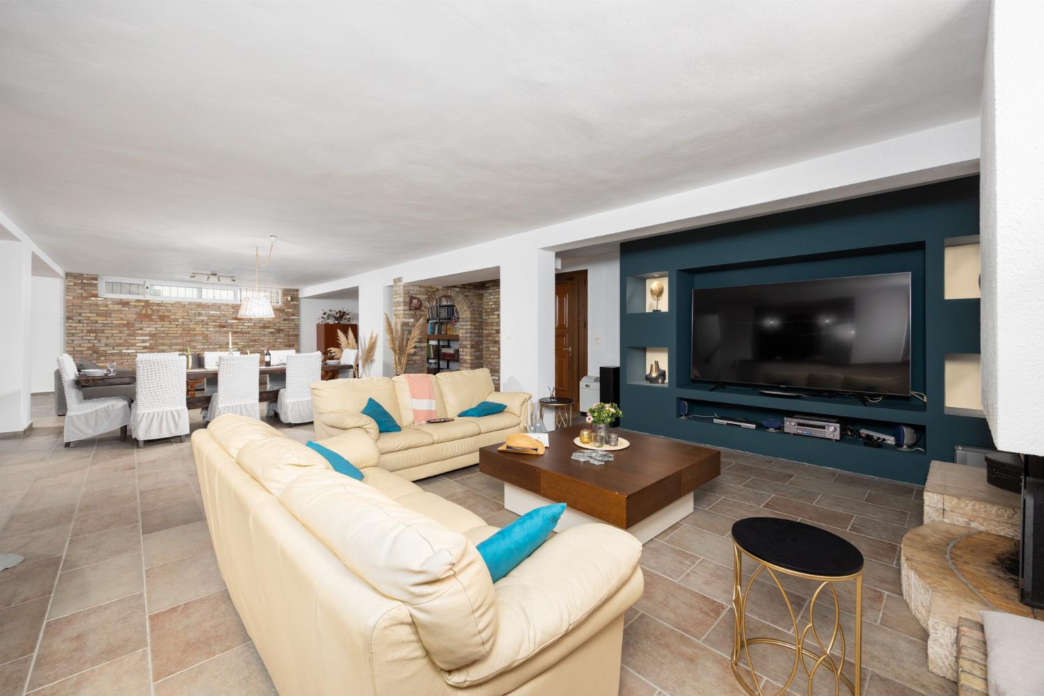 Open-plan living room on ground floor with sofas, dining area, bar area, ornamental fireplace, gym area, WiFi internet, and satellite TV
