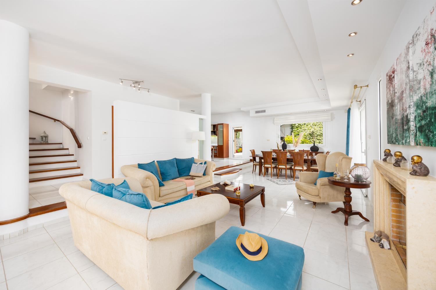 Open-plan living room on first floor with sofas, dining area, kitchen, ornamental fireplace, A/C, and WiFi internet