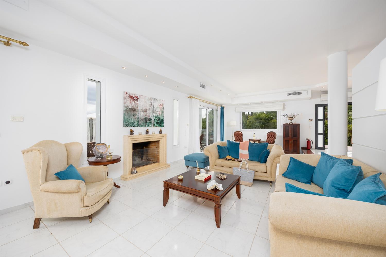 Open-plan living room on first floor with sofas, dining area, kitchen, ornamental fireplace, A/C, and WiFi internet