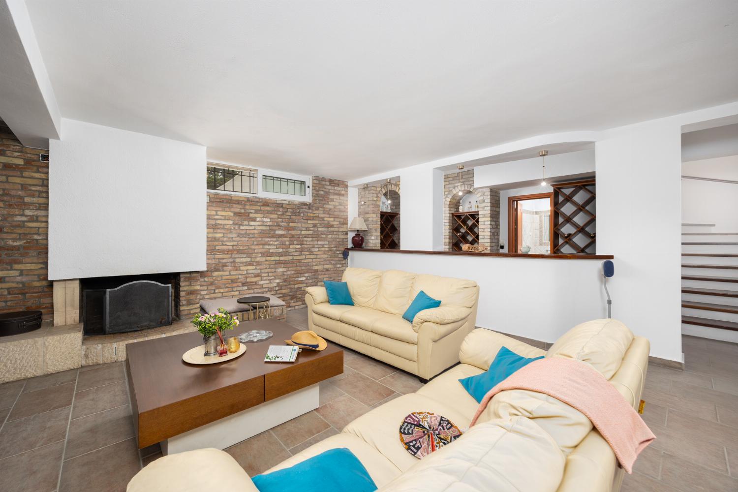 Open-plan living room on ground floor with sofas, dining area, bar area, ornamental fireplace, gym area, WiFi internet, and satellite TV