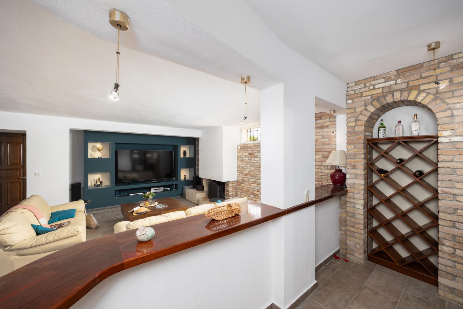 Open-plan living room on ground floor with sofas, dining area, bar area, ornamental fireplace, gym area, WiFi internet, and satellite TV