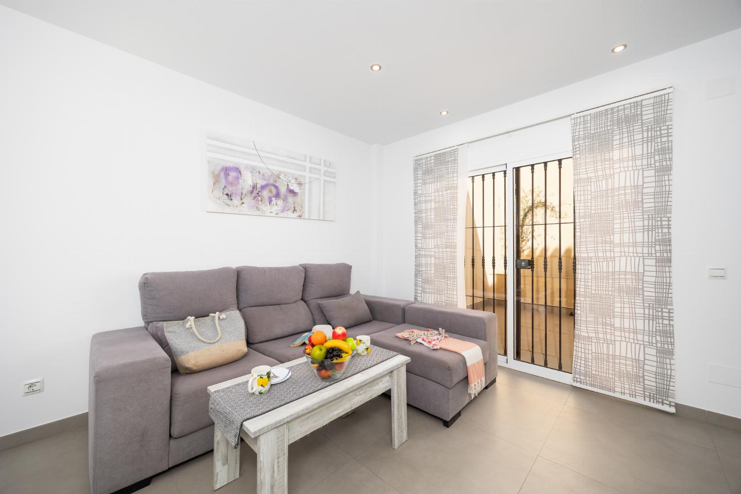Living room with sofa, dining area, A/C, WiFi internet, and satellite TV