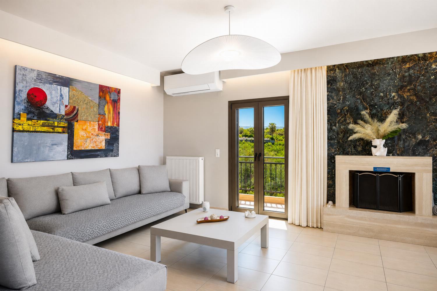 Open-plan living room with sofas, dining area, kitchen, ornamental fireplace, A/C, WiFi internet, and satellite TV