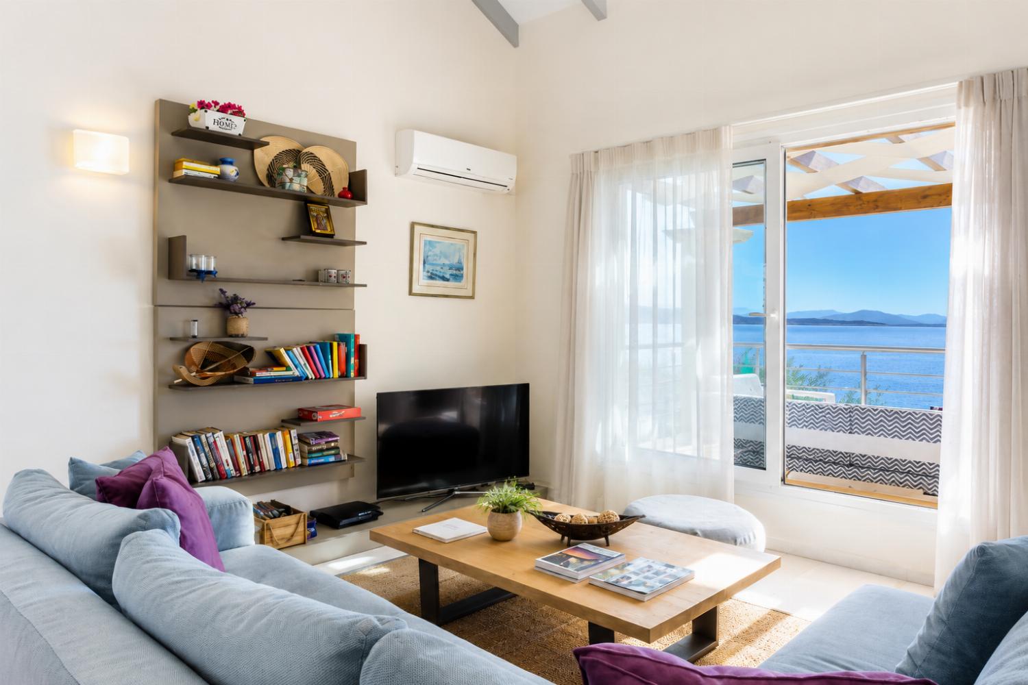 Open-plan living room with sofa, dining area, kitchen, A/C, WiFi internet, and satellite TV