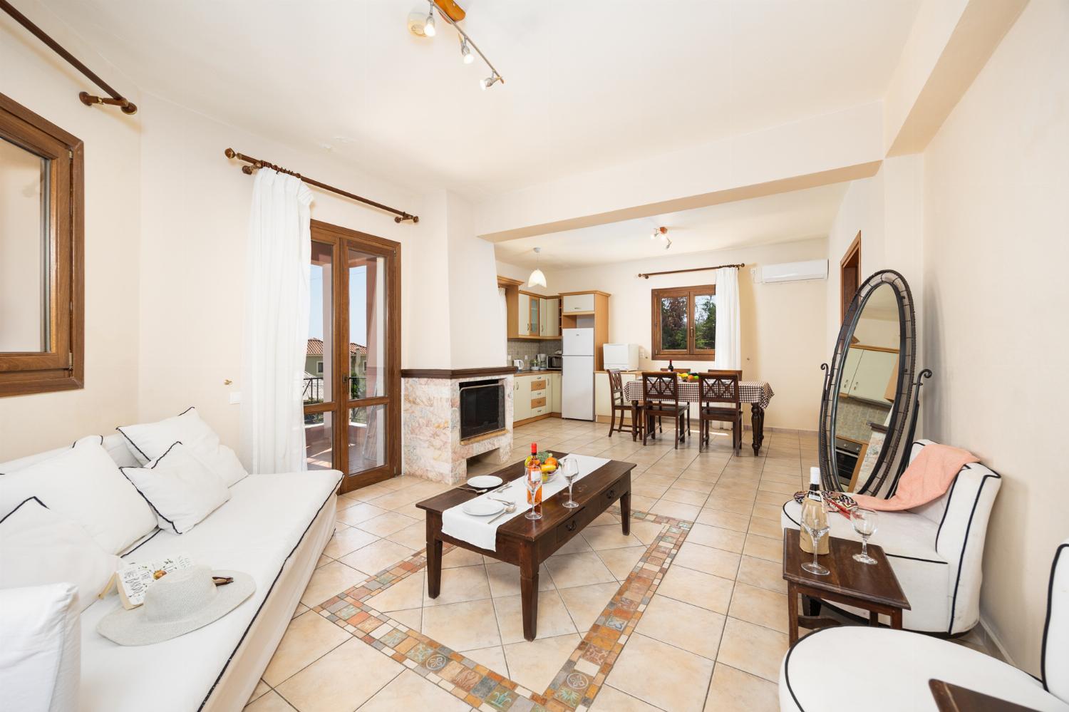 Open-plan living room with sofa, dining area, kitchen, ornamental fireplace, A/C, WiFi internet, and satellite TV