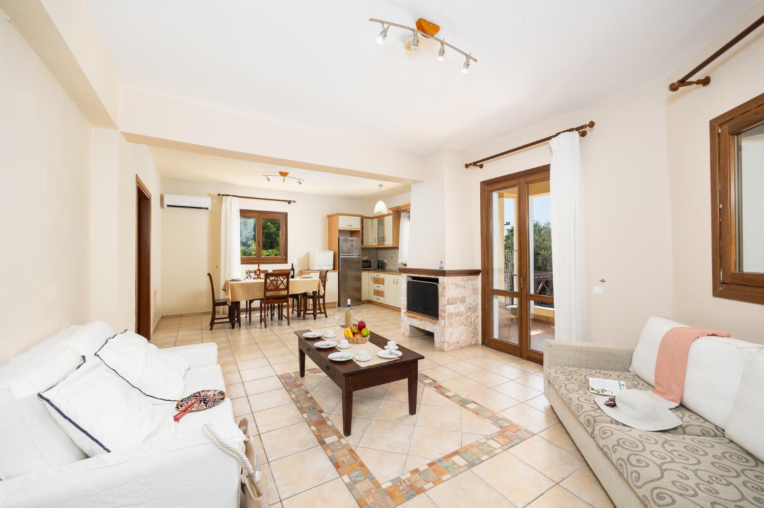Open-plan living room with sofas, dining area, kitchen, ornamental fireplace, A/C, WiFi internet, and satellite TV