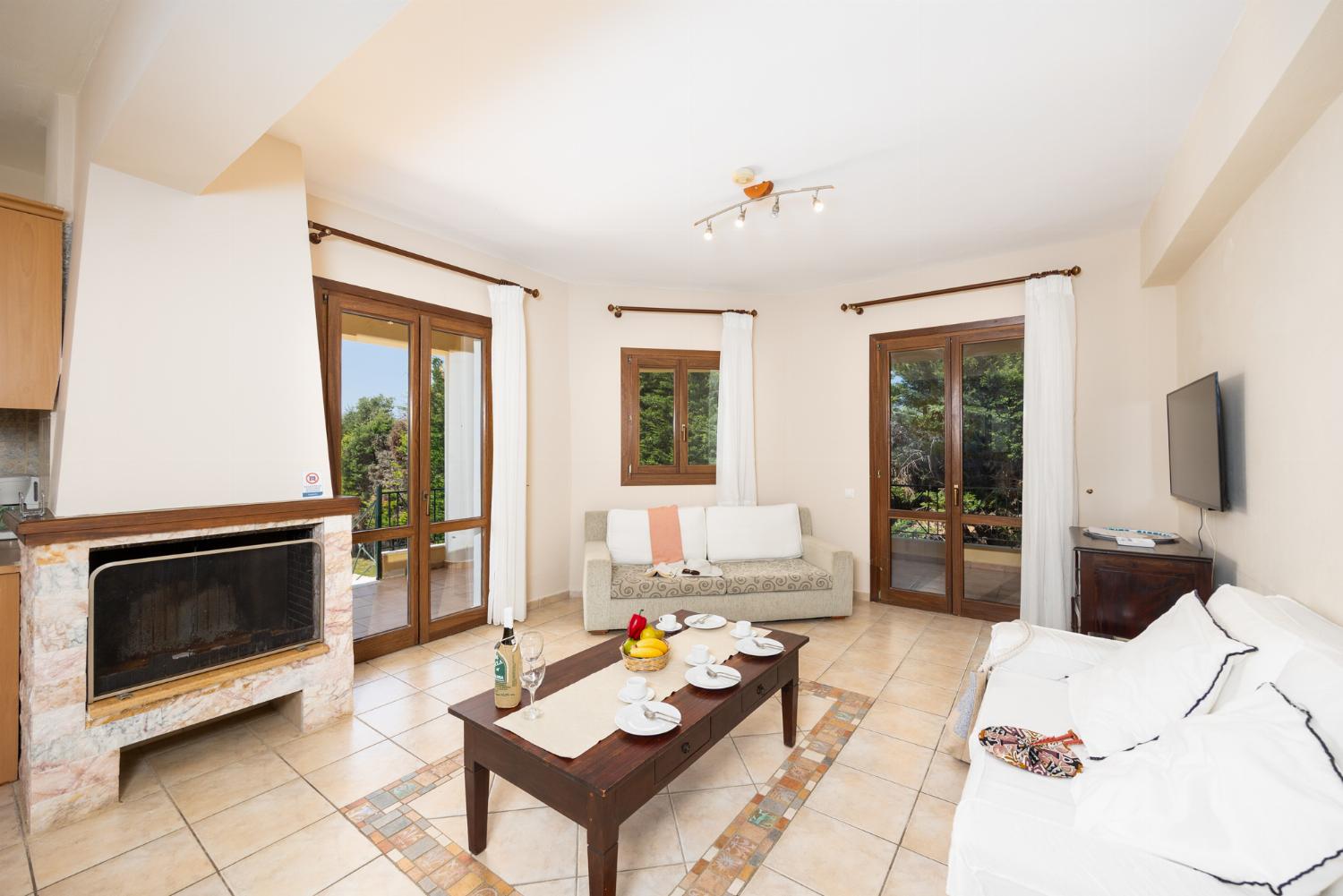 Open-plan living room with sofas, dining area, kitchen, ornamental fireplace, A/C, WiFi internet, and satellite TV
