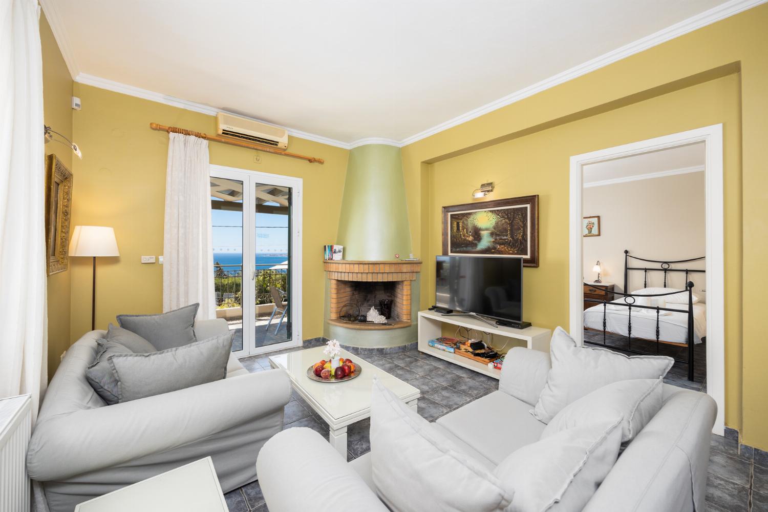 Open-plan living room with sofas, dining area, kitchen, ornamental fireplace, A/C, WiFi internet, satellite TV, and sea views