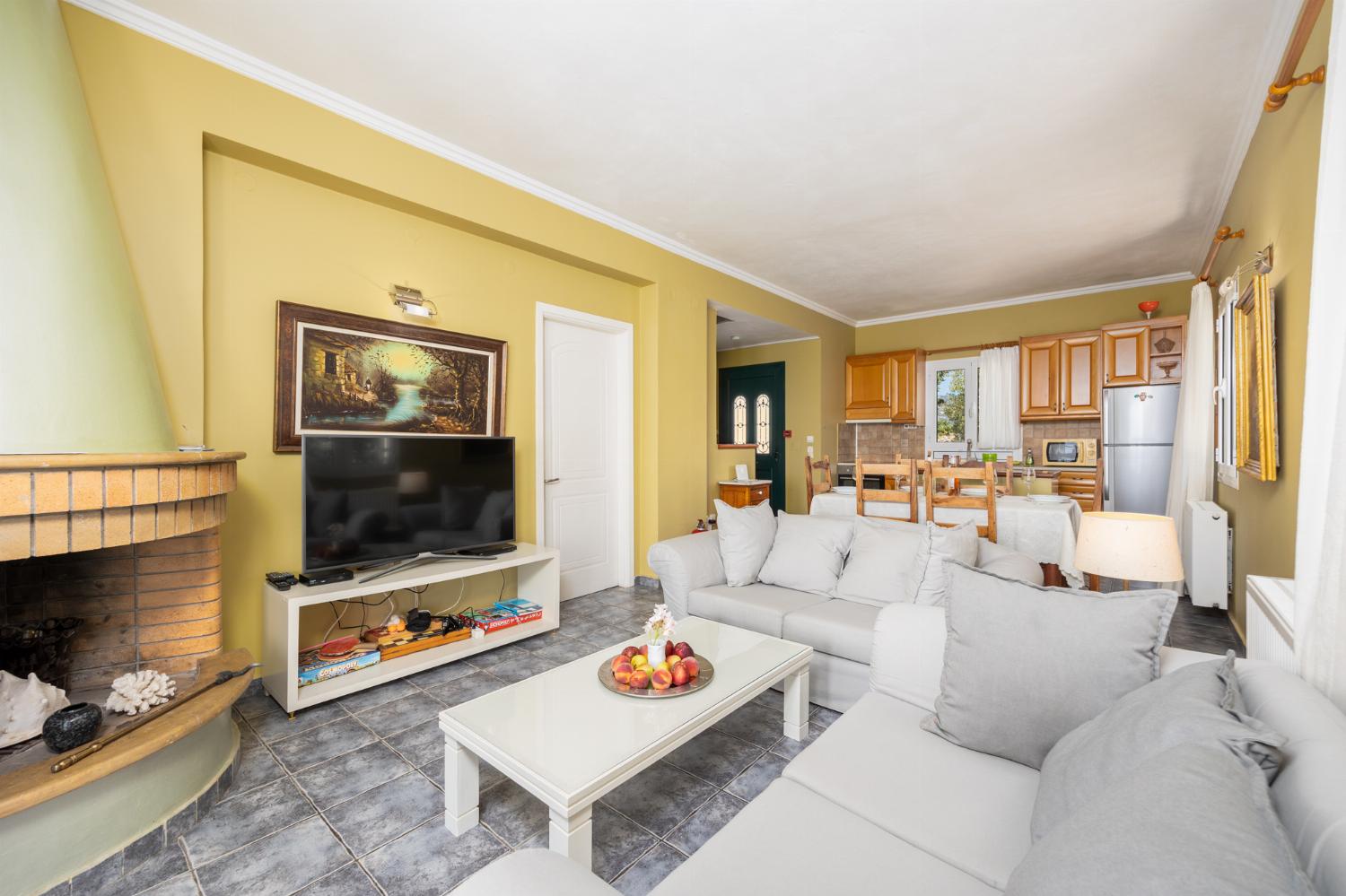 Open-plan living room with sofas, dining area, kitchen, ornamental fireplace, A/C, WiFi internet, satellite TV, and sea views