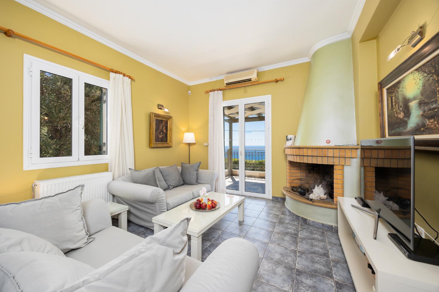 Open-plan living room with sofas, dining area, kitchen, ornamental fireplace, A/C, WiFi internet, satellite TV, and sea views