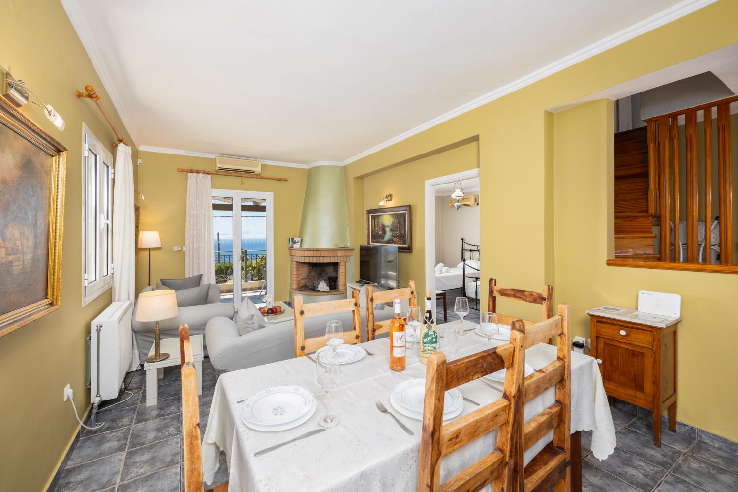 Open-plan living room with sofas, dining area, kitchen, ornamental fireplace, A/C, WiFi internet, satellite TV, and sea views