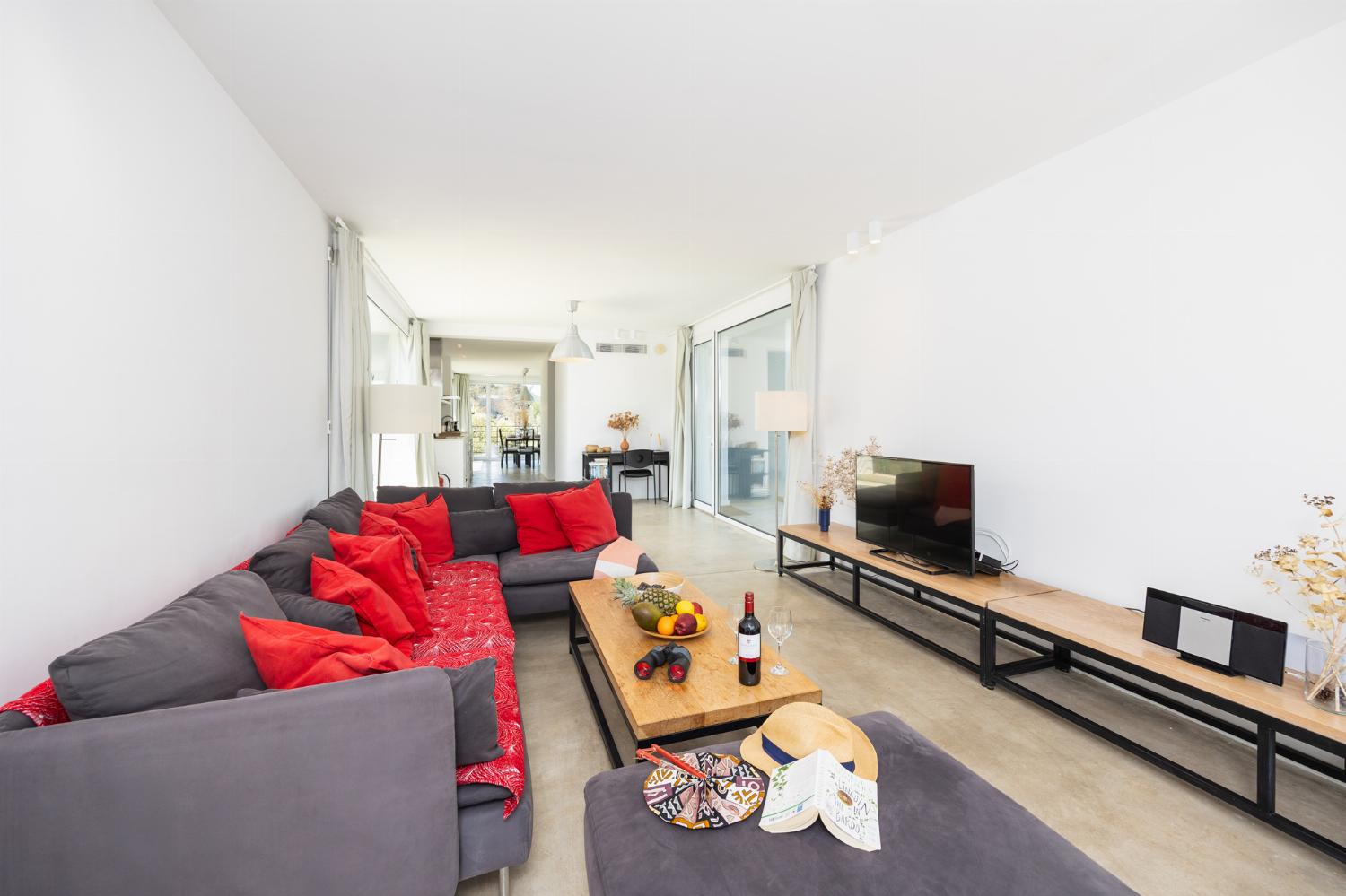 Open-plan living room with sofa, dining area, kitchen, A/C, WiFi internet, and satellite TV