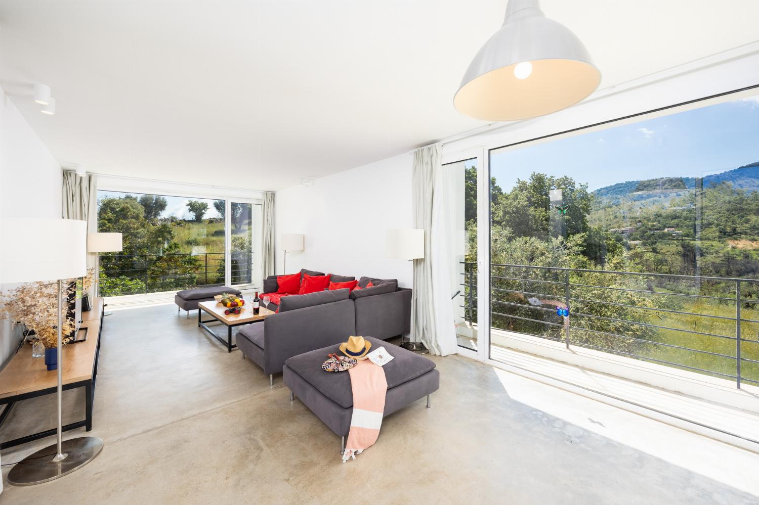 Open-plan living room with sofa, dining area, kitchen, A/C, WiFi internet, and satellite TV
