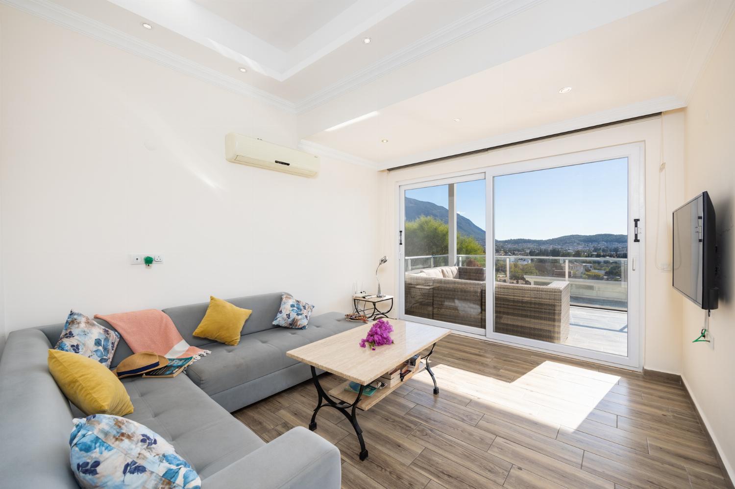 Open-plan living room with sofa, dining area, kitchen, A/C, WiFi internet, and satellite TV