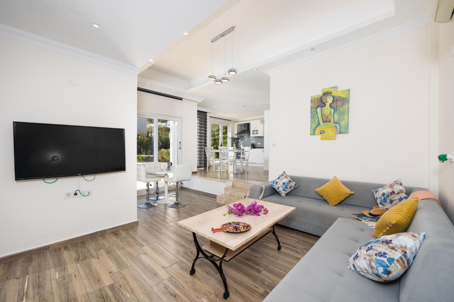 Open-plan living room with sofa, dining area, kitchen, A/C, WiFi internet, and satellite TV