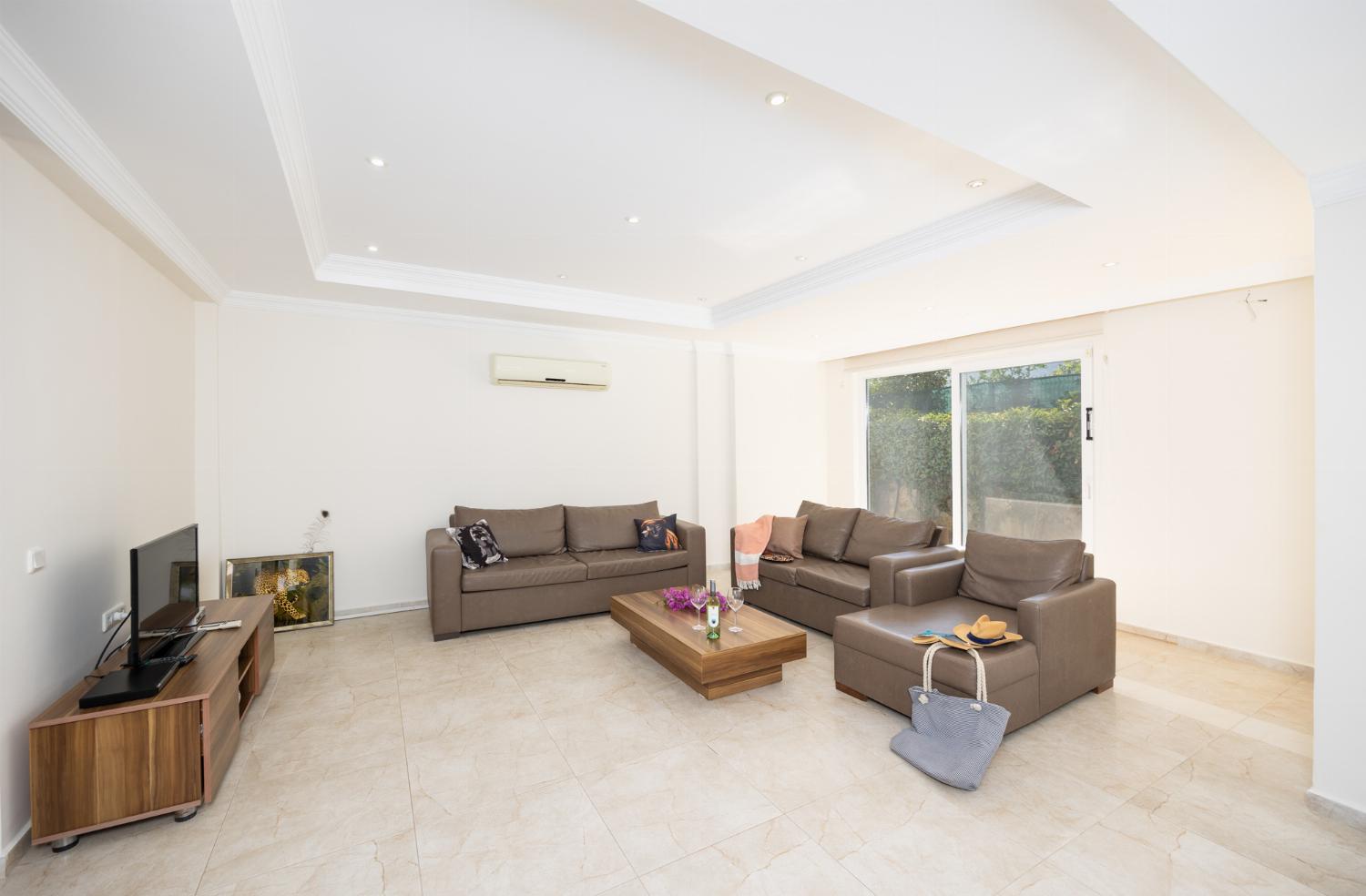 Open-plan living room with sofas, dining area, kitchen, A/C, WiFi internet, and satellite TV