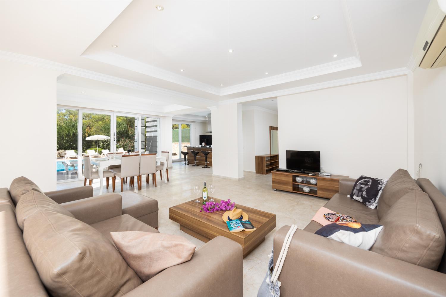 Open-plan living room with sofas, dining area, kitchen, A/C, WiFi internet, and satellite TV